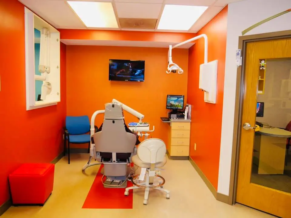 Cheerful and clean, orange pediatric dental treatment room and chair in Florissant MO
